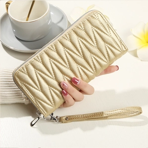 Detailed close-up of a gold quilted long zipper wallet with a matching wristlet strap
