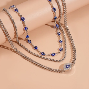 Detail of silver multi-layer necklaces featuring blue evil eye charms and rhinestones