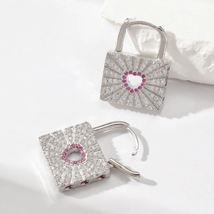 Detail of silver padlock earrings with clear stones and pink heart-shaped center
