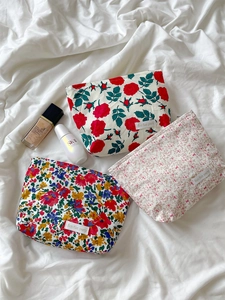 Detailed set of three floral cosmetic bags with zippers on a white soft fabric background