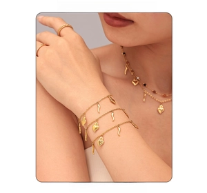 Detail of 18K gold-plated stainless steel heart necklace and layered bracelets on model
