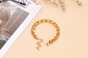 Flat and round double-layered gold stainless steel bracelet on pink background