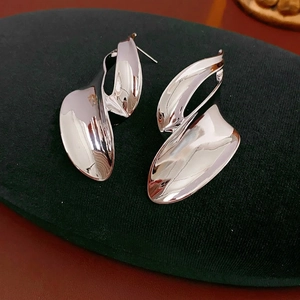 Minimalist silver irregular leaf earrings with polished metallic surface on velvet