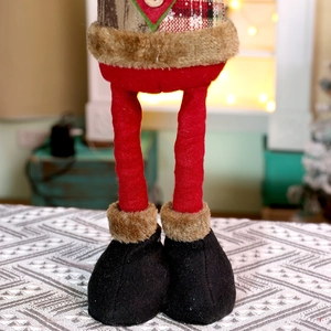 Details von weihnachtlichen Plüschpuppenbeinen mit rotem Karo und Kunstpelzstiefeln