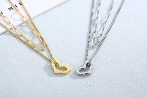 Detail of layered gold and silver necklaces featuring irregular heart-shaped pendants