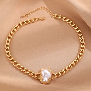 Detail of golden Cuban chain necklace with baroque pearl on champagne silk fabric