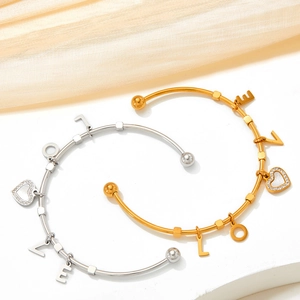 Gold and silver stainless steel LOVE charm bangles with heart crystals on white silk