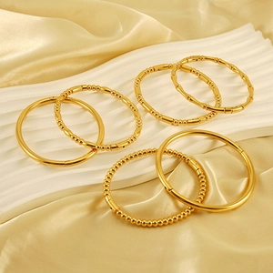 Dettaglio dei bracciali rigidi in acciaio inossidabile dorato con design a bambù