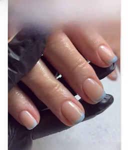 Nahaufnahme von kurzen quadratischen French Nails mit nackter Basis und hellblauen Spitzen
