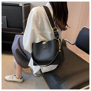 Detail of black pebbled leather bucket bag with a stylish black and white woven strap