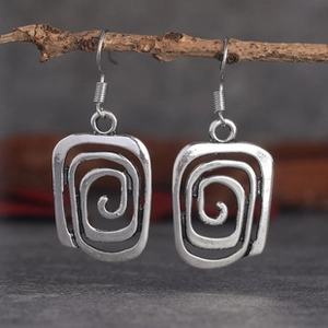Detailed view of vintage hollow spiral earrings in antique silver on wood branch