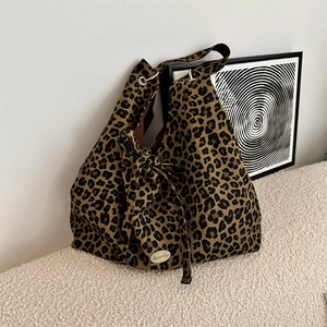 Close-up of leopard print canvas tote bag with metal brand logo on textured fabric