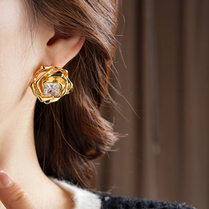 Vue détaillée de boucles d'oreilles fleur en or 18k avec gemme carrée sur un modèle