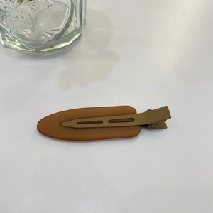 Detail of caramel resin duckbill hair clip with olive green matte metal handle