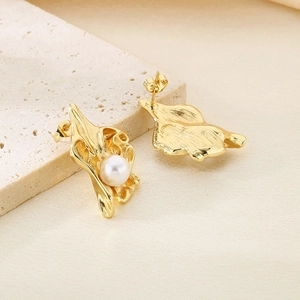 Détail des boucles d'oreilles fleur plissée plaquées or 18k avec une perle blanche douce