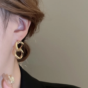 Close-up of elegant double linked gold earrings worn by a model in a minimal setting