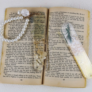 Detail view of handmade resin bookmarks with dried flowers and gold foil on vintage book