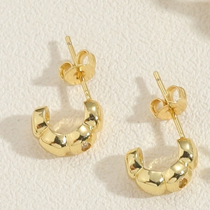 Vista macro degli orecchini a croissant a forma di C placcati in oro 14K con zirconi e farfallina