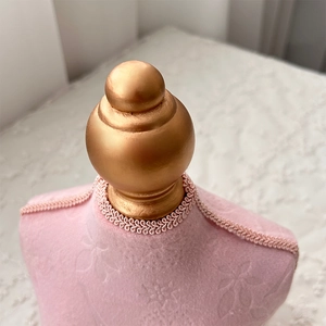 Detail of pink velvet jewelry display bust with embossed floral pattern and gold top ball