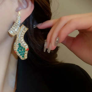 Close-up of vintage gold snake earrings with multicolor rhinestones worn by a model