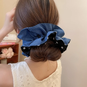 Close-up of double-layer polka dot and denim fabric scrunchie worn on a bun hairstyle