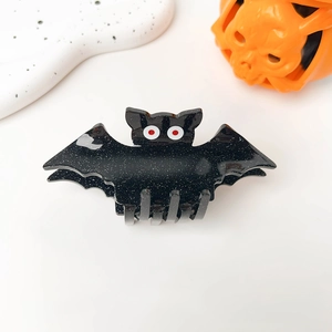 Close-up of Halloween bat hair claw clip with black glitter finish and red eye detail