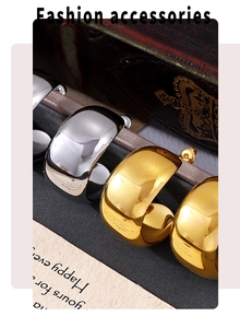 Detailed view of polished C-shaped gold and silver hoop earrings on vintage packaging