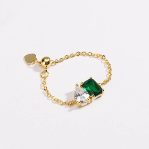 Detail of gold chain ring featuring emerald zircon and white pear-cut stone accents