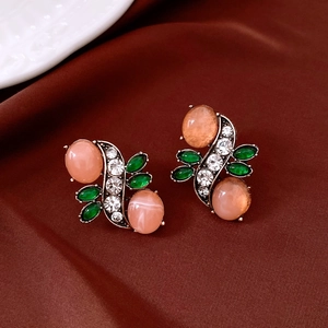 Detailed close-up of vintage bronze earrings with peach resin gems and green accents