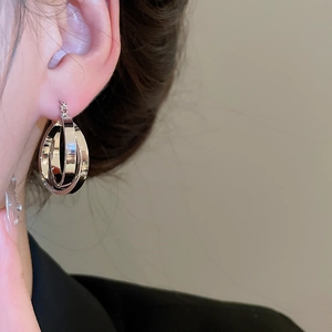 Close-up of triple-layered interlocking silver hoop earrings shown on a model's ear