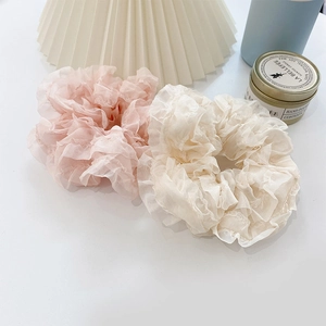 Close-up of pink and cream lace scrunchies in lightweight pleated mesh fabric