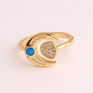 Detail of moon-shaped gold-plated ring featuring blue gemstone and inlaid crystals
