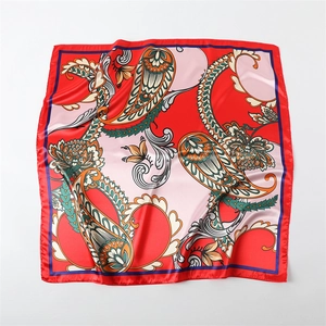 Dettaglio ravvicinato del motivo paisley su un foulard quadrato in raso di seta rosso e rosa