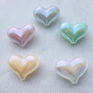 Detail showing five iridescent heart-shaped resin beads in assorted pastel colors