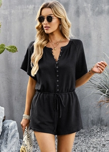 Detail of a black short sleeve romper with button-down front and adjustable drawstring waist