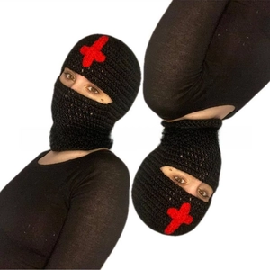 Detail of black knitted balaclava with red cross embroidery and warm winter texture