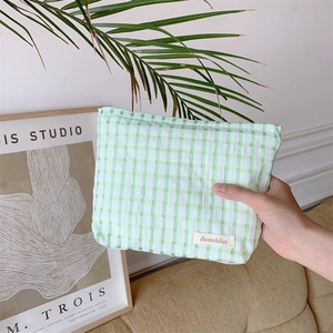 Detail of green and white plaid makeup bag featuring Sozakka label in hand