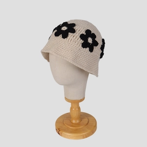 Détail du chapeau cloche au crochet crème avec fleurs noires 3D sur support en bois