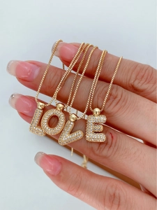 Close-up of luxury gold letter necklaces spelling LOVE with sparkling crystal pavé