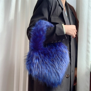 Close-up of fluffy electric blue faux fur heart bag styled with a black blazer jacket
