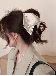 Détail d'un nœud en satin champagne élégant avec bouton doré sur une queue de cheval