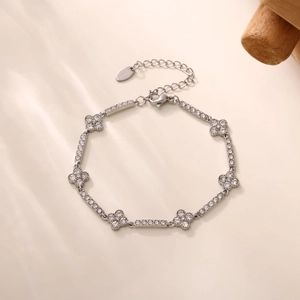 Detail of silver clover bracelet with sparkling zircons on a warm background