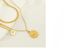 Detail of gold double-layer necklace featuring flat snake chain and heart pendant