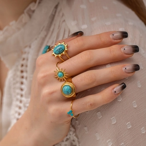 Détail d'un ensemble de bagues dorées bohèmes avec pierres turquoises sur une main