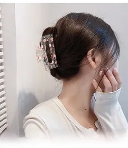 Rear view of a large acrylic hair claw clip with festive Santa Claus and candy cane prints