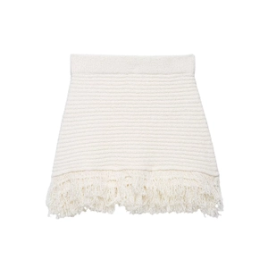 Détail d'une jupe en maille blanche avec des finitions à franges denses sur l'ourlet du bas