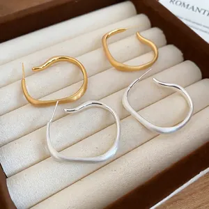 Irregular matte C-shaped hoop earrings in gold and silver finish with wave texture