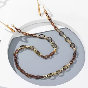 Macro detail of amber acrylic eyeglass chain with gold metal links and rubber ends