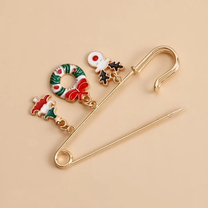 Detail of Christmas safety pin brooch with wreath, elk, and tree charms in gold finish
