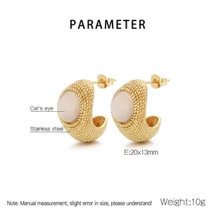 Detailed view of C-shaped gold-plated earrings with cat's eye stone inlay and textured finish